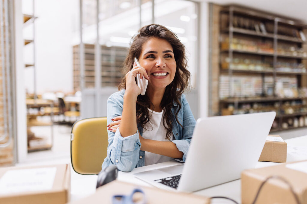 Cheerful businesswoman speaking on the phone in a warehouse | ANG
