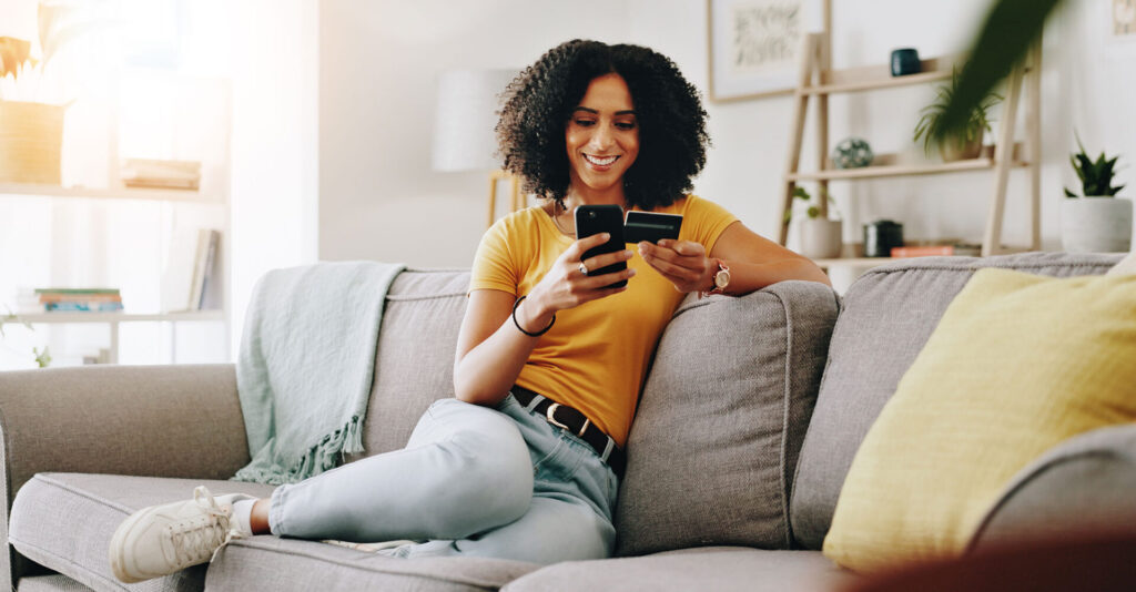 Credit card happy and woman on sofa with phone for online shopping web store sale and purchase e1753294303967 | ANG