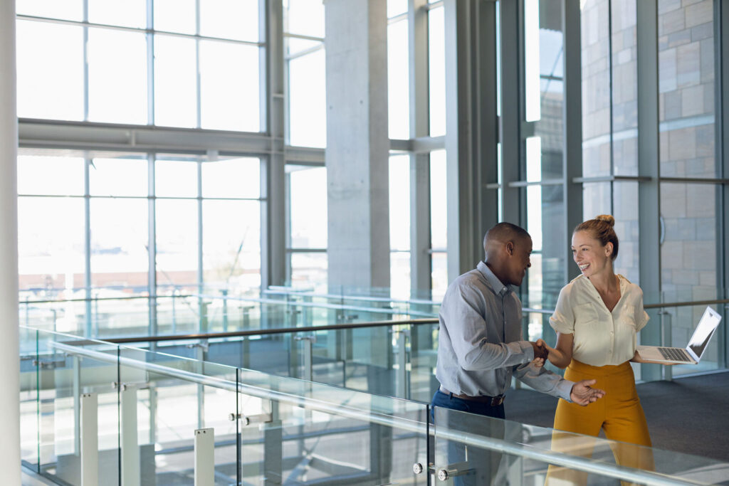 Young business people shaking hands in modern office lobby | ANG