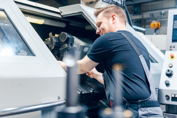 Maschinenbau - Experienced-worker-changing-tool-setup-of-lathe-machine