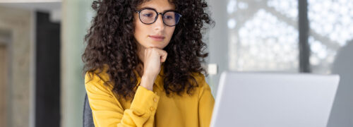 Frau sitzt am Laptop mit gelber Bluse