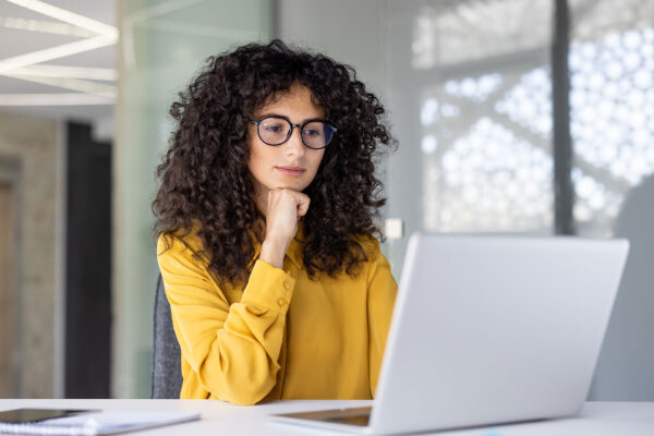 Frau sitzt am Laptop mit gelber Bluse